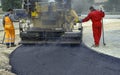 Worker regulate tracked paver laying asphalt