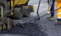 Worker leads the vibrating road roller to compact