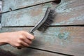 Worker remove old paint on wooden wall with metal brush berore p