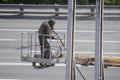 A worker removes old paint from road barriers using an air compressor.