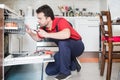 Worker repairing the dishwasher in the kitchen Royalty Free Stock Photo