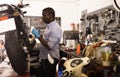 Worker repairing failed scooter in motorcycle garage Royalty Free Stock Photo