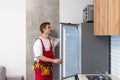 Worker repairing fridge in kitchen Royalty Free Stock Photo