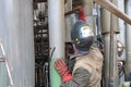 Worker repairman fitter welders in a mask repairing a pipeline, brewing a pipe, repairing equipment at an oil refining Royalty Free Stock Photo