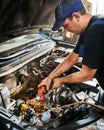 Worker, repairman, mechanic wearing cap and uniform, repairing car.