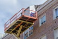 Worker repairs the facade of a residential building on a basket of an industrial lift
