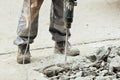 A worker repairs the road surface with a jackhammer on a summer day. Construction works on the road. Royalty Free Stock Photo