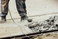 A worker repairs the road surface with a jackhammer on a summer day. Construction works on the road. Royalty Free Stock Photo