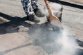 Worker repairs the roof with molten tar from a bucket with a broom. Roof repair tar