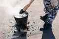 Worker repairs the roof with molten tar from a bucket with a broom. Roof repair tar