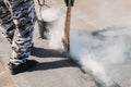 Worker repairs the roof with molten tar from a bucket with a broom