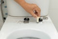 Worker replace hinge rubber plug and Screws for Toilet Seat Royalty Free Stock Photo