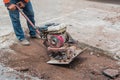 Worker reversible plate compactor on a roadwork site.