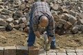 Worker: road builder laying cobblestones