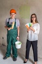 Worker with roller and paint bucket and woman with colour sampler