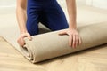 Worker rolling out new carpet flooring indoors, closeup Royalty Free Stock Photo