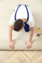 Worker rolling out new carpet flooring indoors, top view Royalty Free Stock Photo