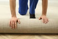 Worker rolling out new carpet flooring indoors, closeup Royalty Free Stock Photo