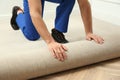 Worker rolling out new carpet flooring indoors, closeup Royalty Free Stock Photo