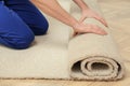 Worker rolling out new carpet flooring indoors, closeup Royalty Free Stock Photo