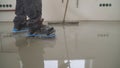 A worker rolls out the liquid floor with a trowel. Squeegee for distributing the mixture. The worker levels the liquid floor.