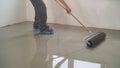 A worker rolls out the liquid floor with a trowel. Squeegee for distributing the mixture. The worker levels the liquid