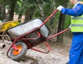 Worker rolls over a cart with garbage in a landfill, close-up