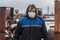 Worker on the roof of the factory in an dirty uniform. a disposable dressing on the face.