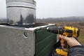 A worker on the roof of the house sheathes the chimney with a metal profile