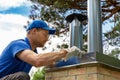 Worker on the roof installing tin cap on the brick chimney Royalty Free Stock Photo