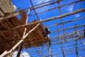 Worker is roofing with leaves. Wooden structure house with blue sky