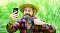 Worker in rural farm. farmer with lilac flower in beard. Ecology. Green field in summer. Countryman making selfie on