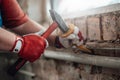 Builder`s gloved hands working with hammer and chisel at the construction site