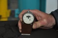 worker's hand holds a dial gauge for measuring the hardness