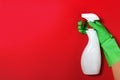 Worker`s hand in a rubber green protective glove with a spray bottle on a red color background. The concept of cleaning, home car Royalty Free Stock Photo