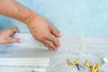 Worker`s hands Instal plastic skirting board on laminate flooring. Renovation of baseboard at home