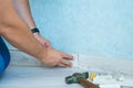 Worker`s hands Instal plastic skirting board on laminate flooring. Renovation of baseboard at home.