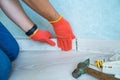 Worker`s hands Instal plastic skirting board on laminate flooring. Renovation of baseboard at home. Royalty Free Stock Photo