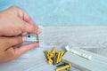 Worker`s hands Instal plastic skirting board on laminate flooring. Renovation of baseboard at home. Royalty Free Stock Photo