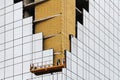 Worker on the scaffold elevator evens insulation boards at the corner of building