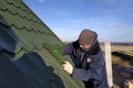 The worker screws the snow retaining elements to the roof with a screwdriver