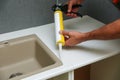 Worker seals kitchen sink with sealant.