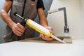 Worker seals kitchen sink with sealant.