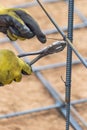 Hands of Worker Using Tools To Bend Steel Rebar At Construction Site