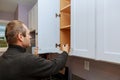 Worker sets a new handle on the white cabinet with a screwdriver installing kitchen cabinets Royalty Free Stock Photo