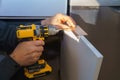 Worker sets a new handle on the white cabinet with a screwdriver installing kitchen cabinets Royalty Free Stock Photo