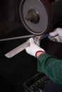 Worker sharpening and grinding knife in factory setting sanding wheel manufacturing closeup