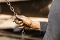 Worker at a shipyard in Dhaka Bangladesh holds a chain of a chain hoist with his oil-smeared hands