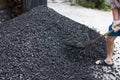 A worker with a shovel unloads black coal against the background of a large pile of coal. Soft focus