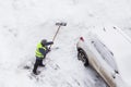 Man shoveling snow after snowfall near car on road